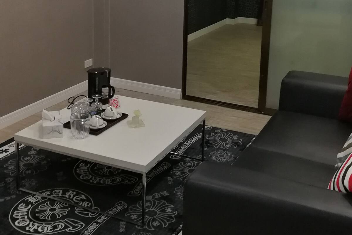 A modern living room with a white coffee table, black sofa, and a large mirror.