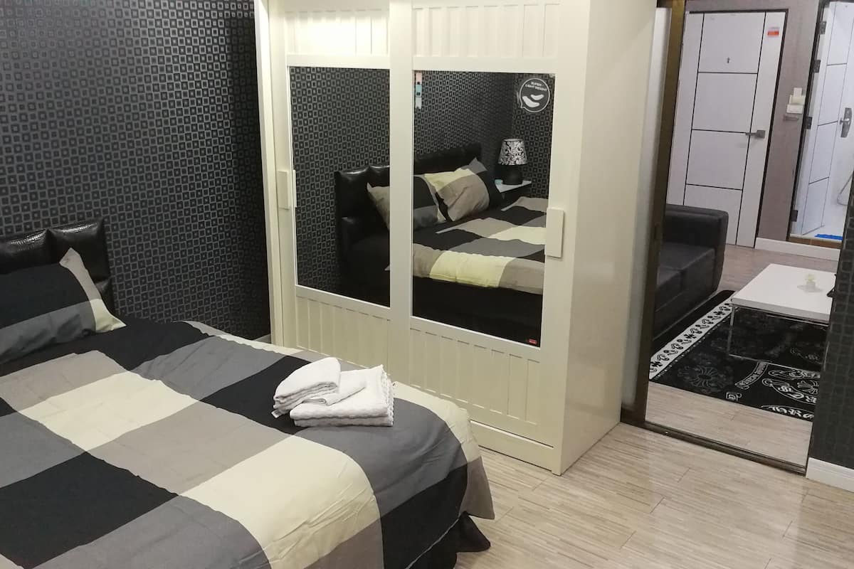 A hotel room with a bed, a wardrobe, a mirror, and a small table.