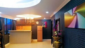 A modern kitchen with a central island, a refrigerator, and a clock on the wall. - Hotler Boutique Apartment (Pattaya)