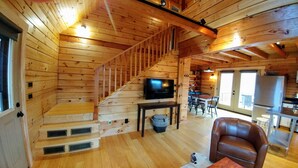 A wooden cabin interior with a staircase, a television, a dining area, and a kitchen. - Peacefull, private Cabin! 140 acres,mile of river trails! 10 minutes to Rt.151! (Faber)