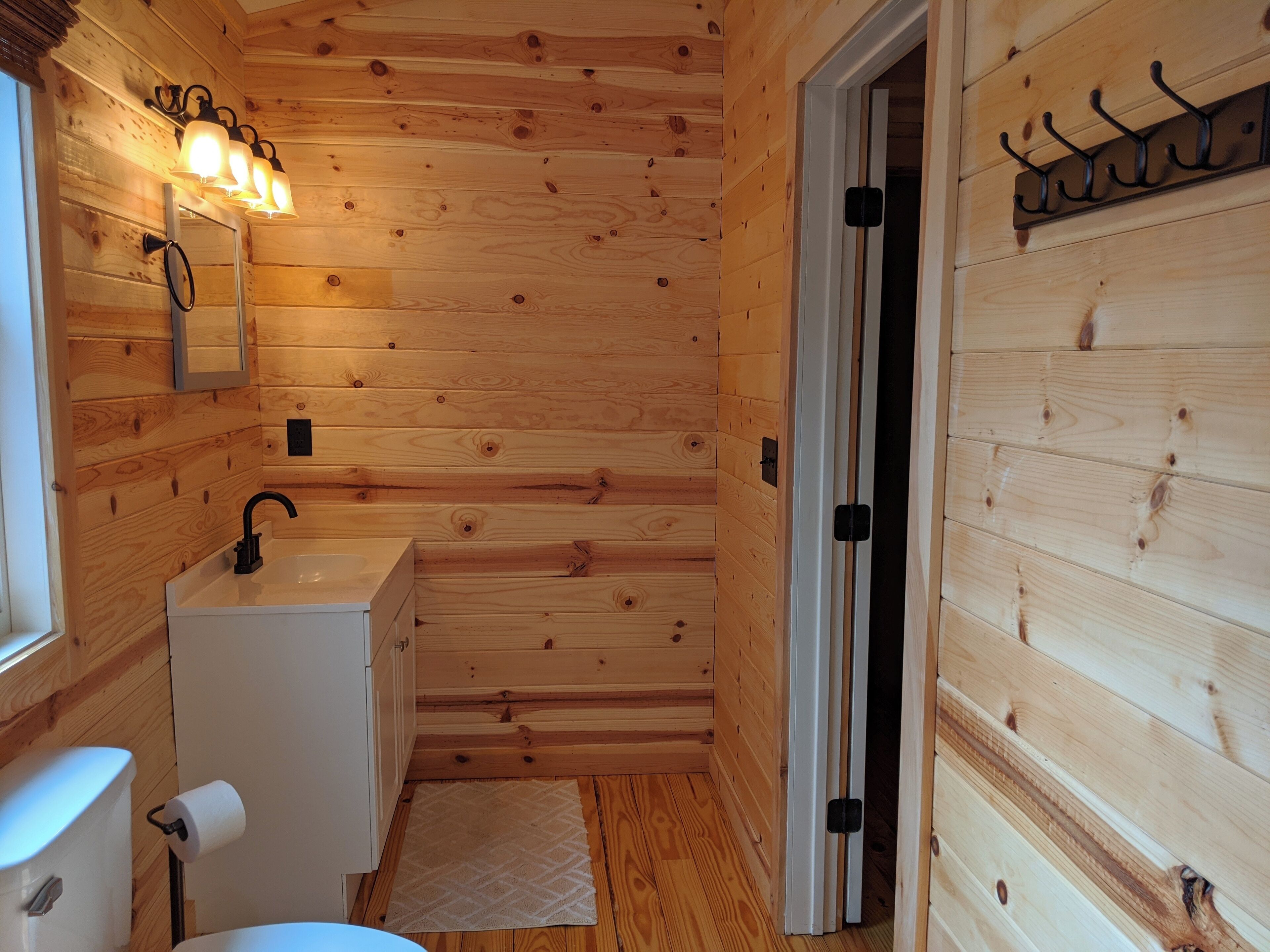A wooden cabin bathroom with a sink, mirror, and towel dispenser.