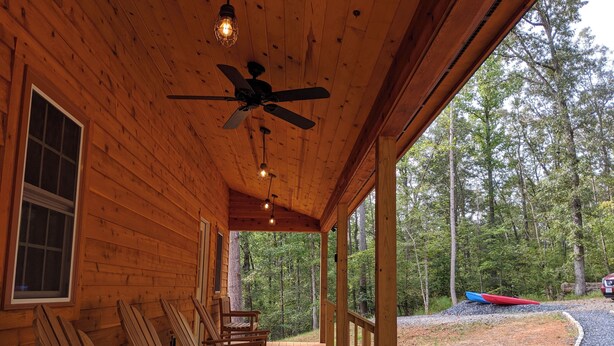 A wooden cabin with a porch, ceiling fan, and seating area. - Peacefull, private Cabin! 140 acres,mile of river trails! 10 minutes to Rt.151! (Faber)