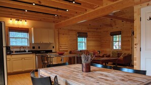 A wooden cabin interior with a kitchen, dining area, and living space. - Peacefull, private Cabin! 140 acres,mile of river trails! 10 minutes to Rt.151! (Faber)
