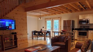 A cozy living room with a wooden coffee table, leather sofa, and a TV on the wall. - Peacefull, private Cabin! 140 acres,mile of river trails! 10 minutes to Rt.151! (Faber)