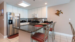 A modern kitchen with white cabinets, stainless steel appliances, and a central island with bar stools.