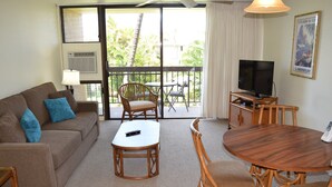 Una habitación con sofá, mesa de centro, televisor y mesa de comedor con sillas.