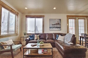 Uma sala de estar com um sofá de couro marrom, uma mesa de centro de madeira e um quadro na parede.