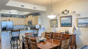 A modern kitchen with wooden cabinets, a stainless steel refrigerator, and a dining area with a wooden table and chairs.