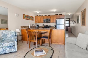 A modern kitchen with wooden cabinets, stainless steel appliances, and a central island with seating. - Second Floor Oceanview with Gorgeous Sunsets (Kihei)