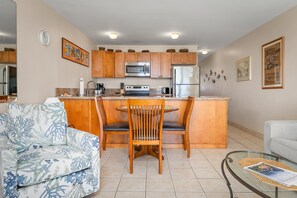 Una cocina compacta con armarios de madera, una isla central y una zona de comedor con dos sillas.