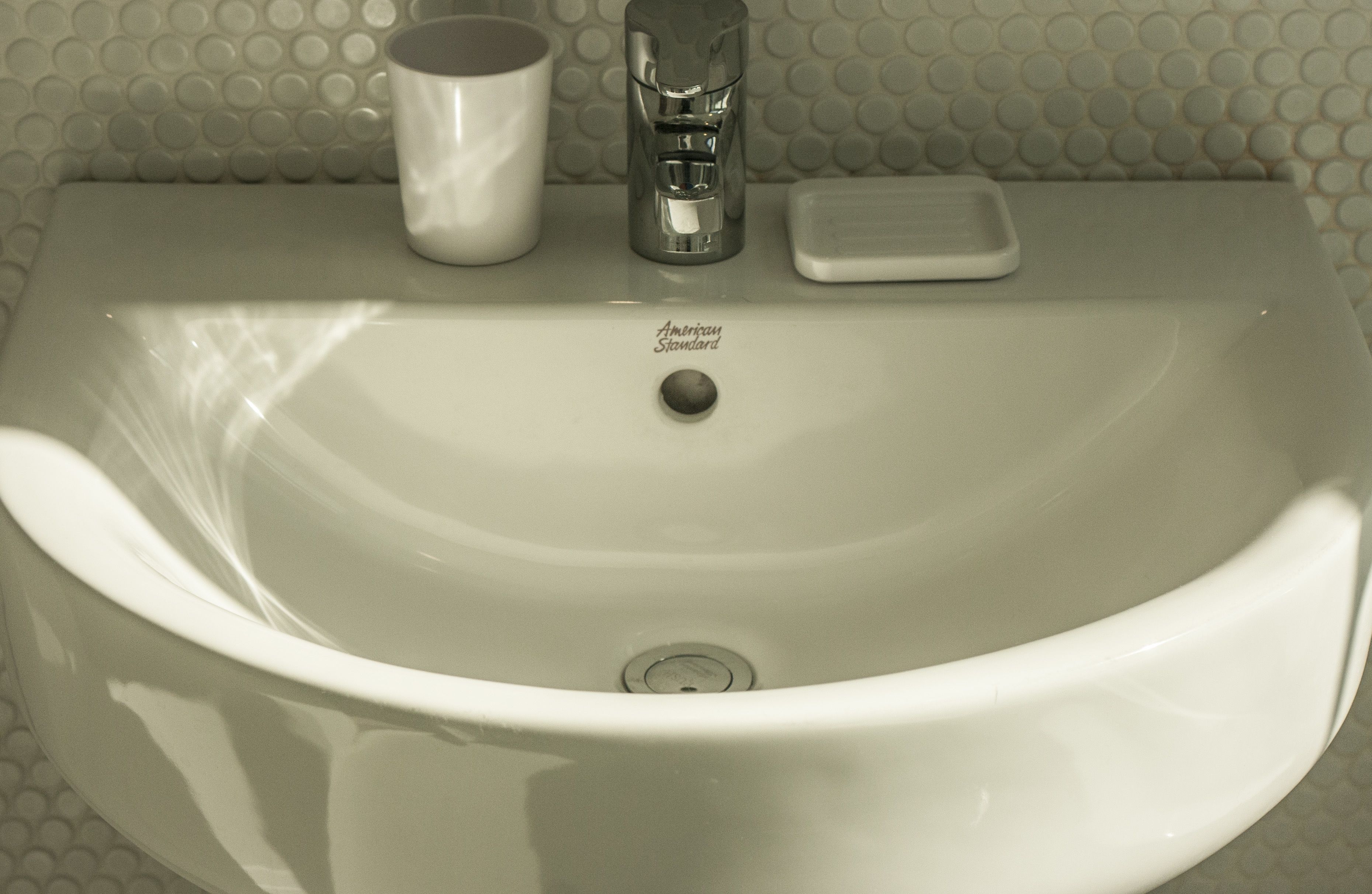 A bathroom sink with a white mug, soap dish, and a faucet.