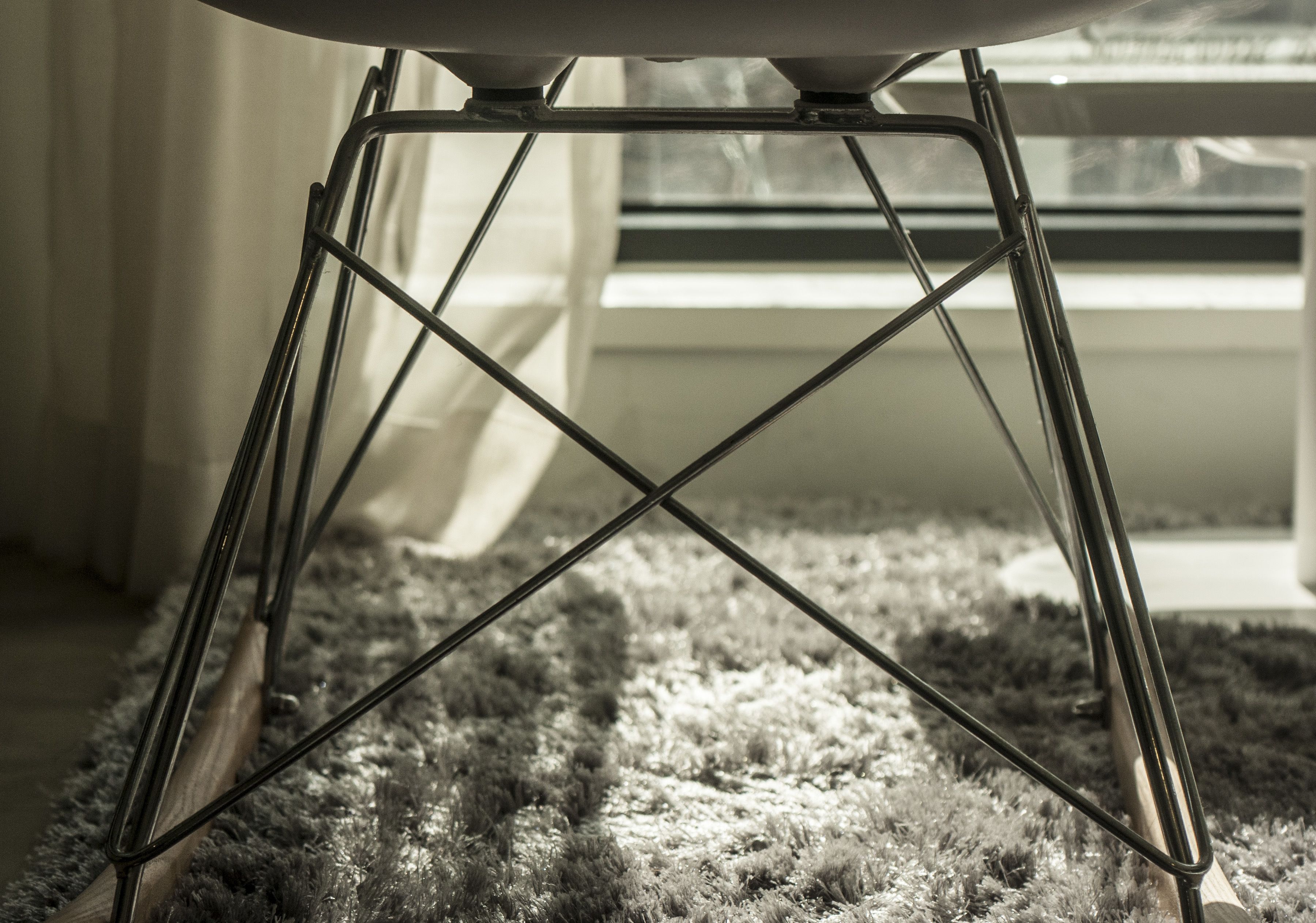 A metal chair with a white seat and backrest, positioned on a textured rug.