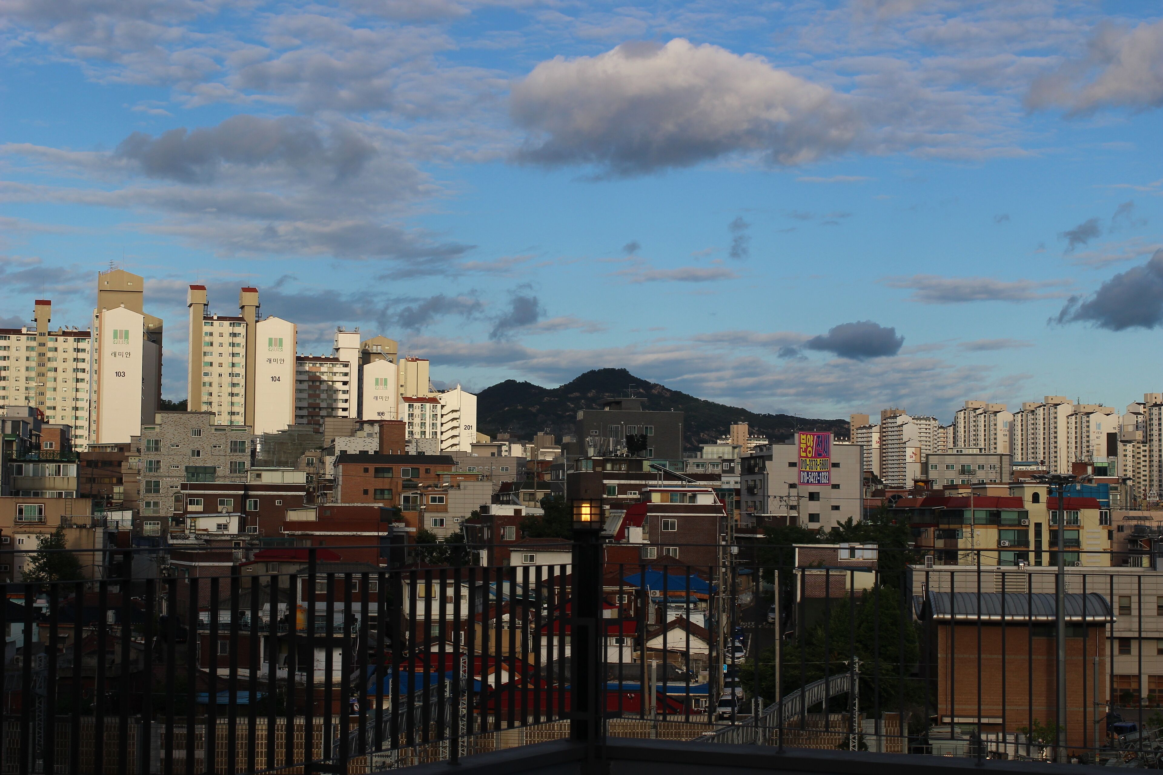 A cityscape with high-rise buildings, a mountain in the background, and a clear sky.