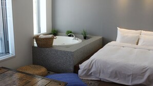Une salle de bain avec une baignoire, un lavabo et une fenêtre avec des stores.