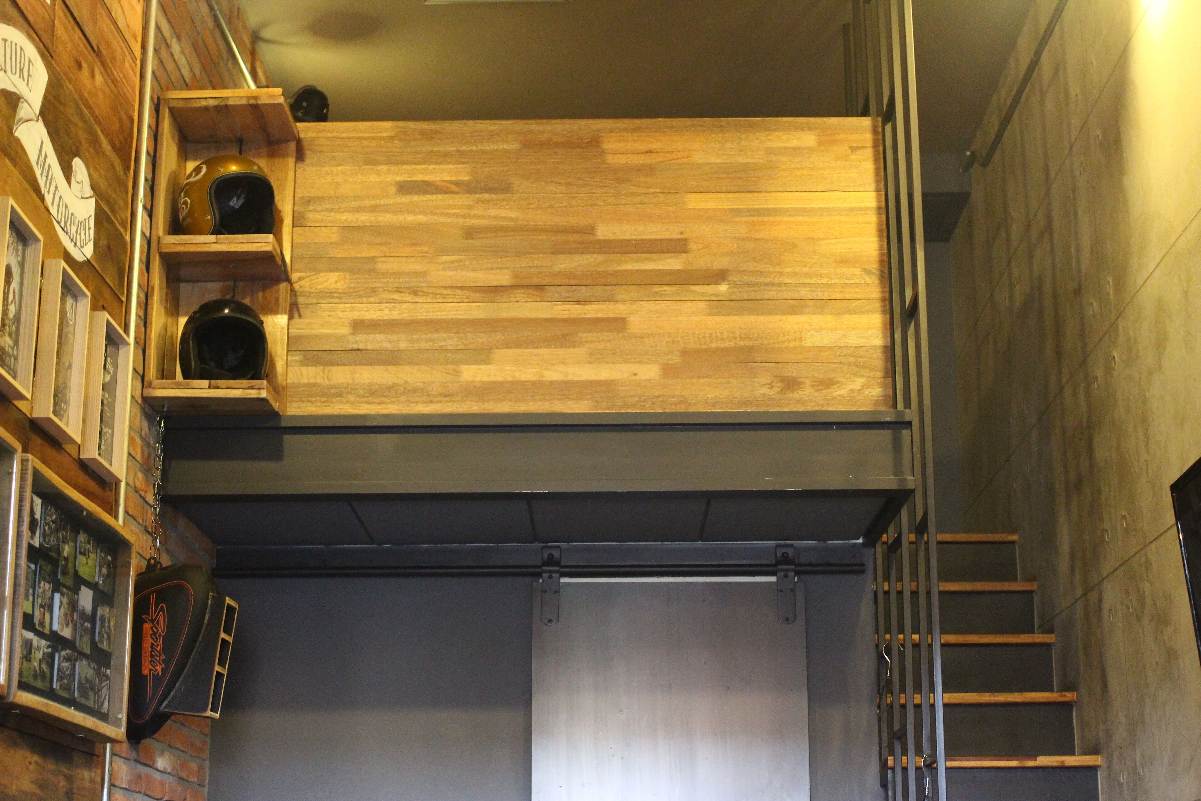 Une pièce de style « loft », avec un plafond en lambris de bois, un escalier en métal et une porte en métal.