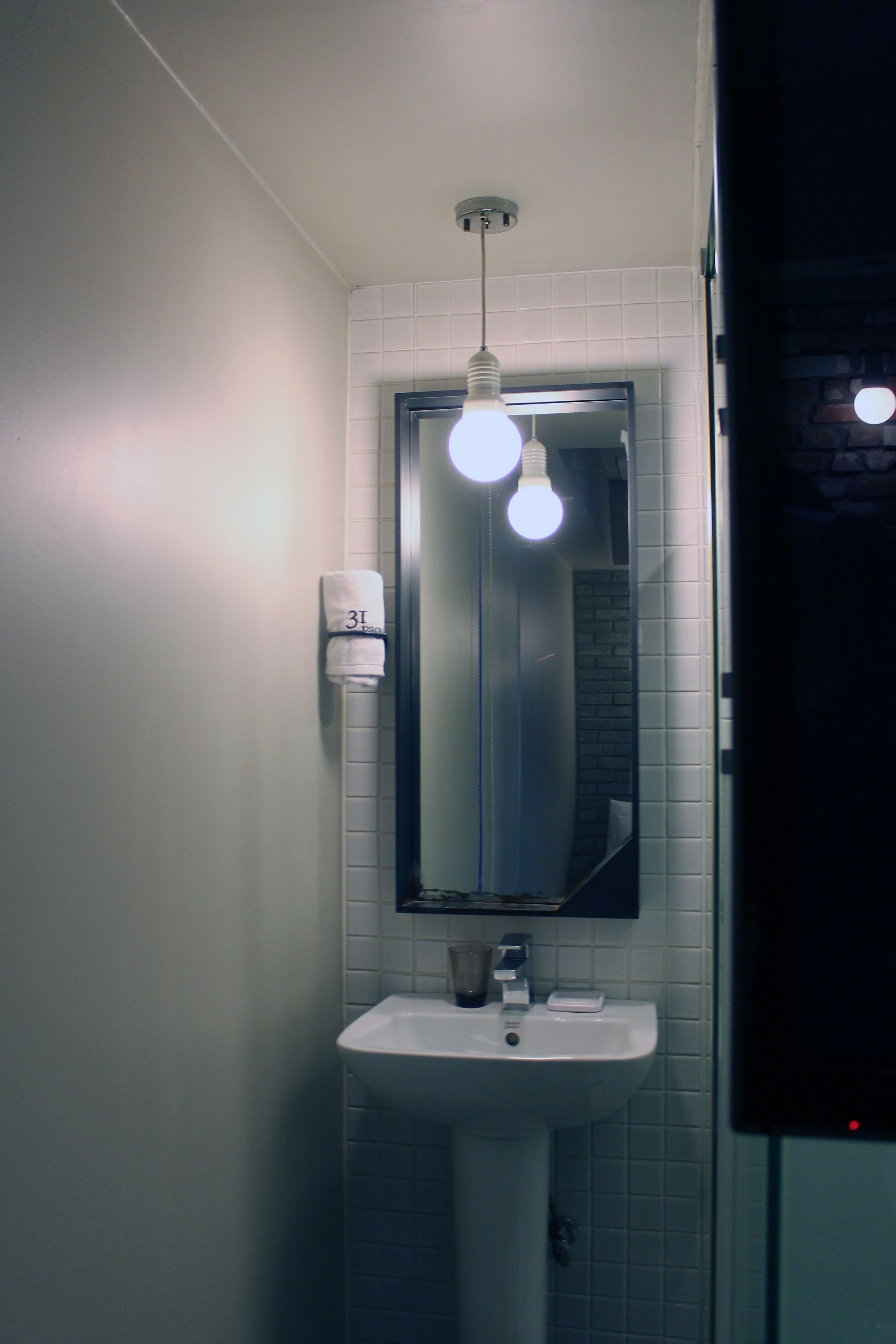Un bagno con un lavandino bianco, uno specchio e un asciugamano appeso al muro.