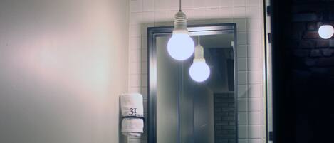 Un bagno con un lavandino bianco, uno specchio e un asciugamano appeso al muro.