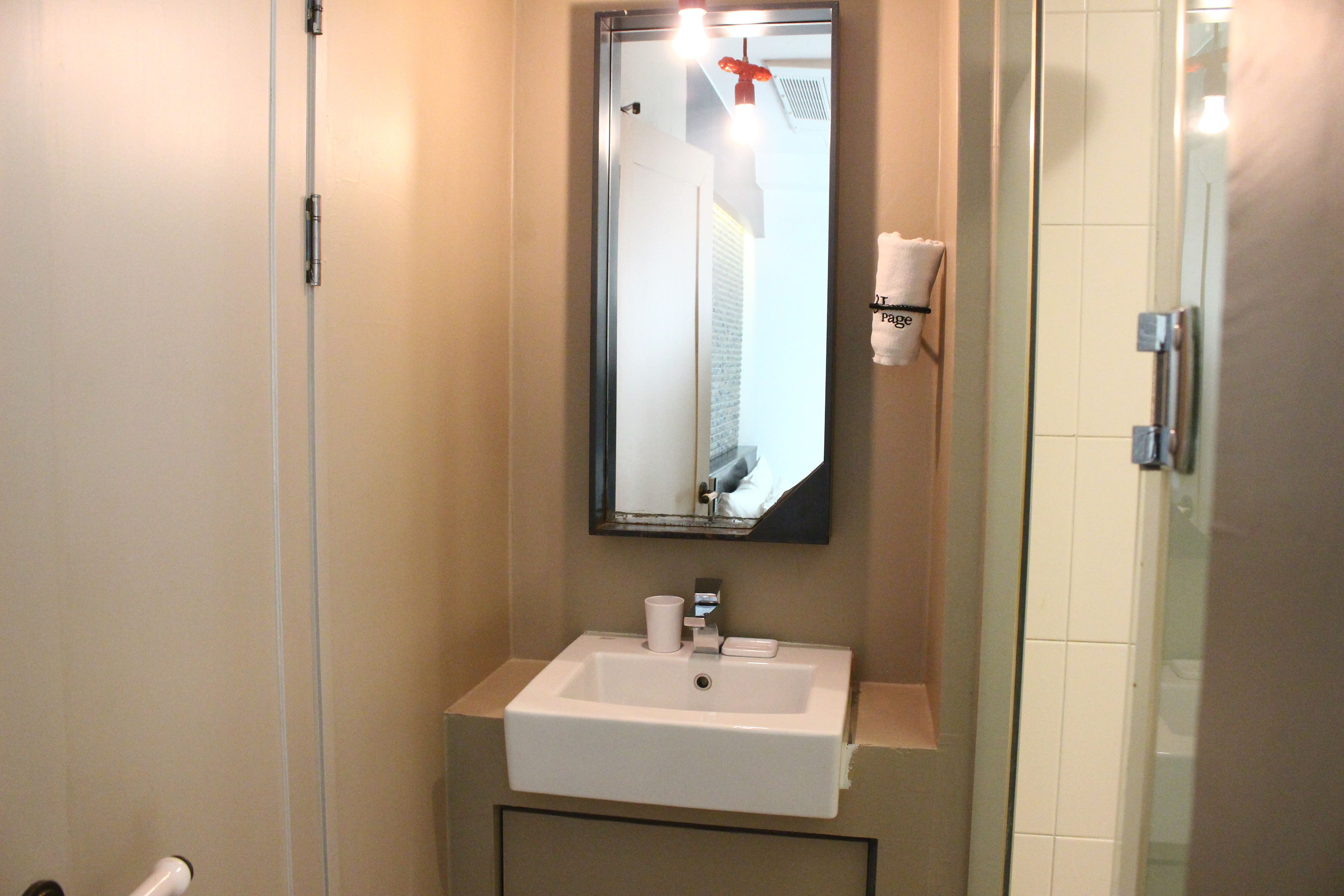 A bathroom with a white sink, a mirror, and a towel rack.