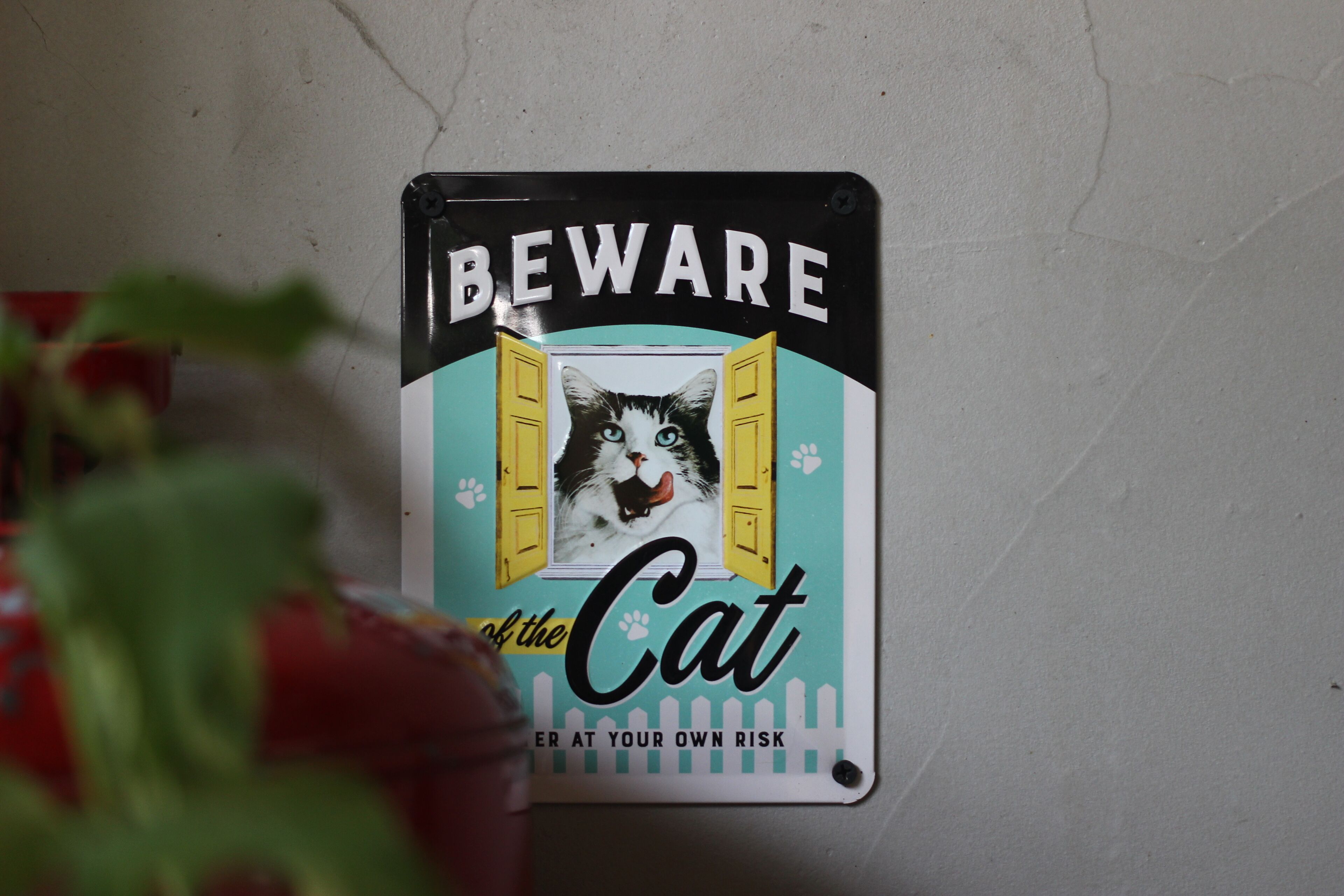 A wall-mounted sign with a warning message and a picture of a cat.
