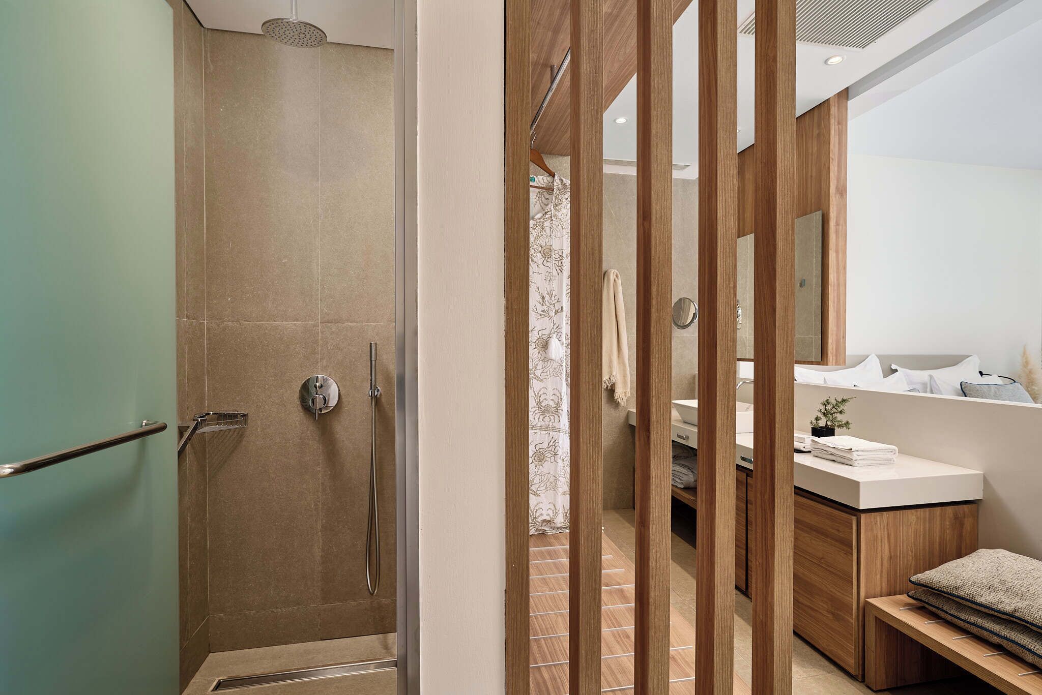 A modern bathroom with a shower, a vanity with a mirror, and a bench.