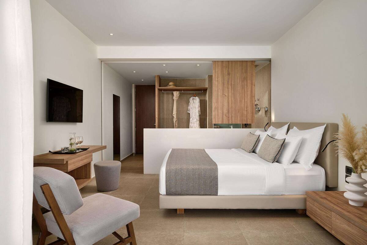 Ein modernes Schlafzimmer mit einem großen Bett, Nachttischen, einem Spiegel und einem Kleiderschrank.