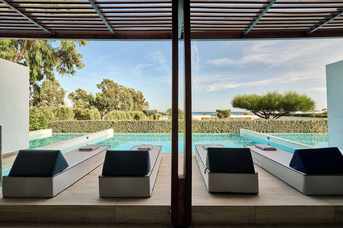 Ein Poolbereich mit Liegestühlen und Blick aufs Meer.