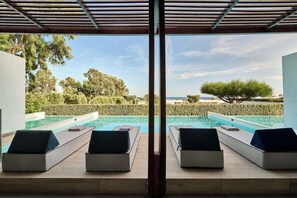 A poolside area with lounge chairs and a view of the sea.