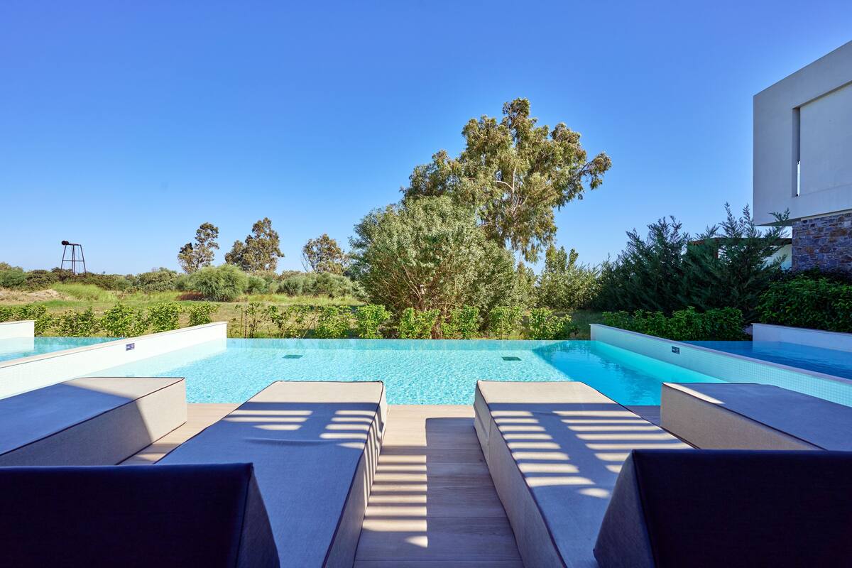 Ein moderner Poolbereich im Freien mit Liegestühlen und freiem Blick auf die umliegende Landschaft.