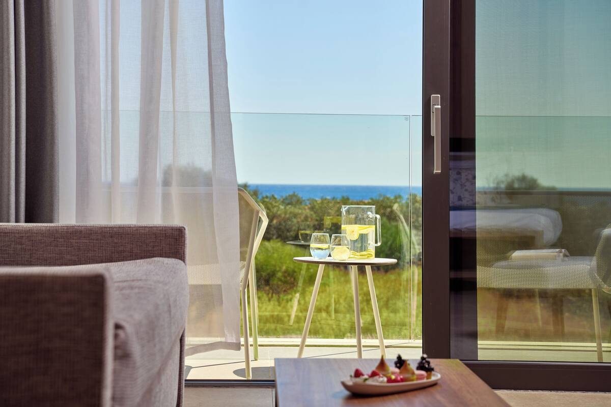 Ein Balkon mit Tisch für zwei, einem Stuhl und Blick auf das Meer.