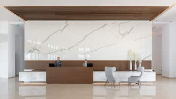 A modern reception area with a marble wall, wooden reception desk, and two white chairs.