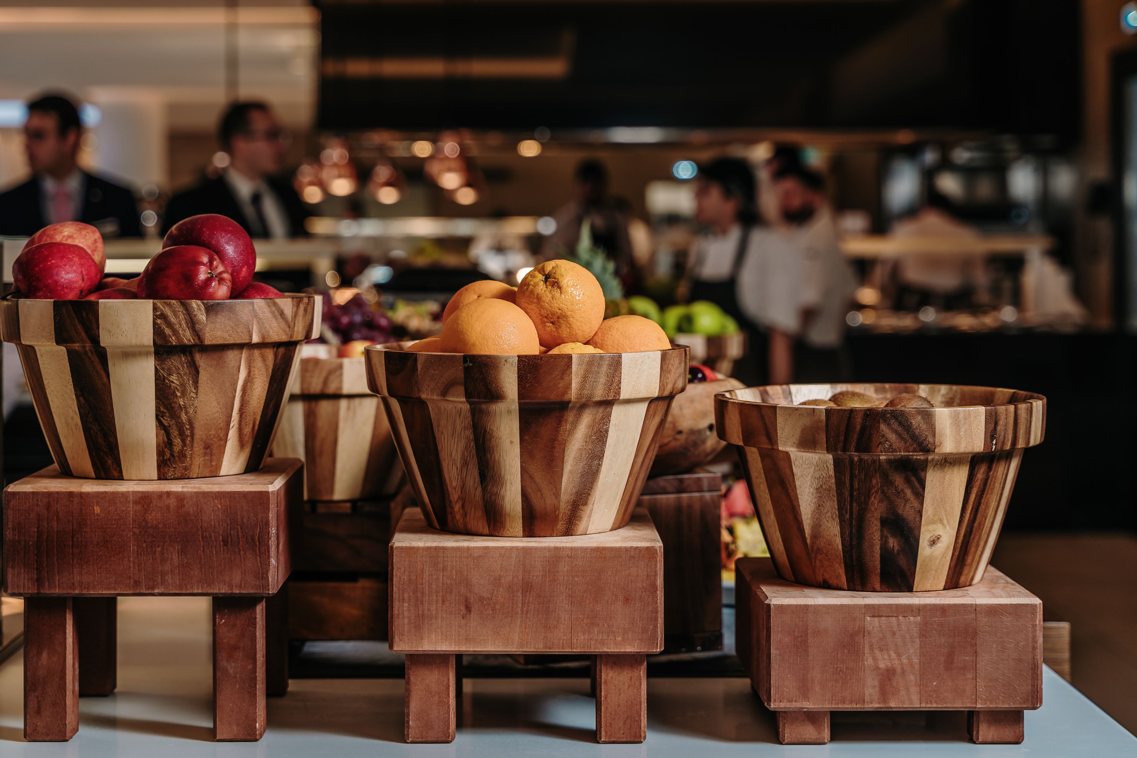 Wooden bowls with fruits on a table in a restaurant setting.
