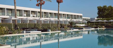 Ein modernes Hotel mit Pool, Palmen und Außenbereich.
