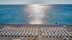 An aerial view of a beach with rows of sunbeds and a boat near the water. - Gennadi Grand Resort - Premium All Inclusive (Rhodes)