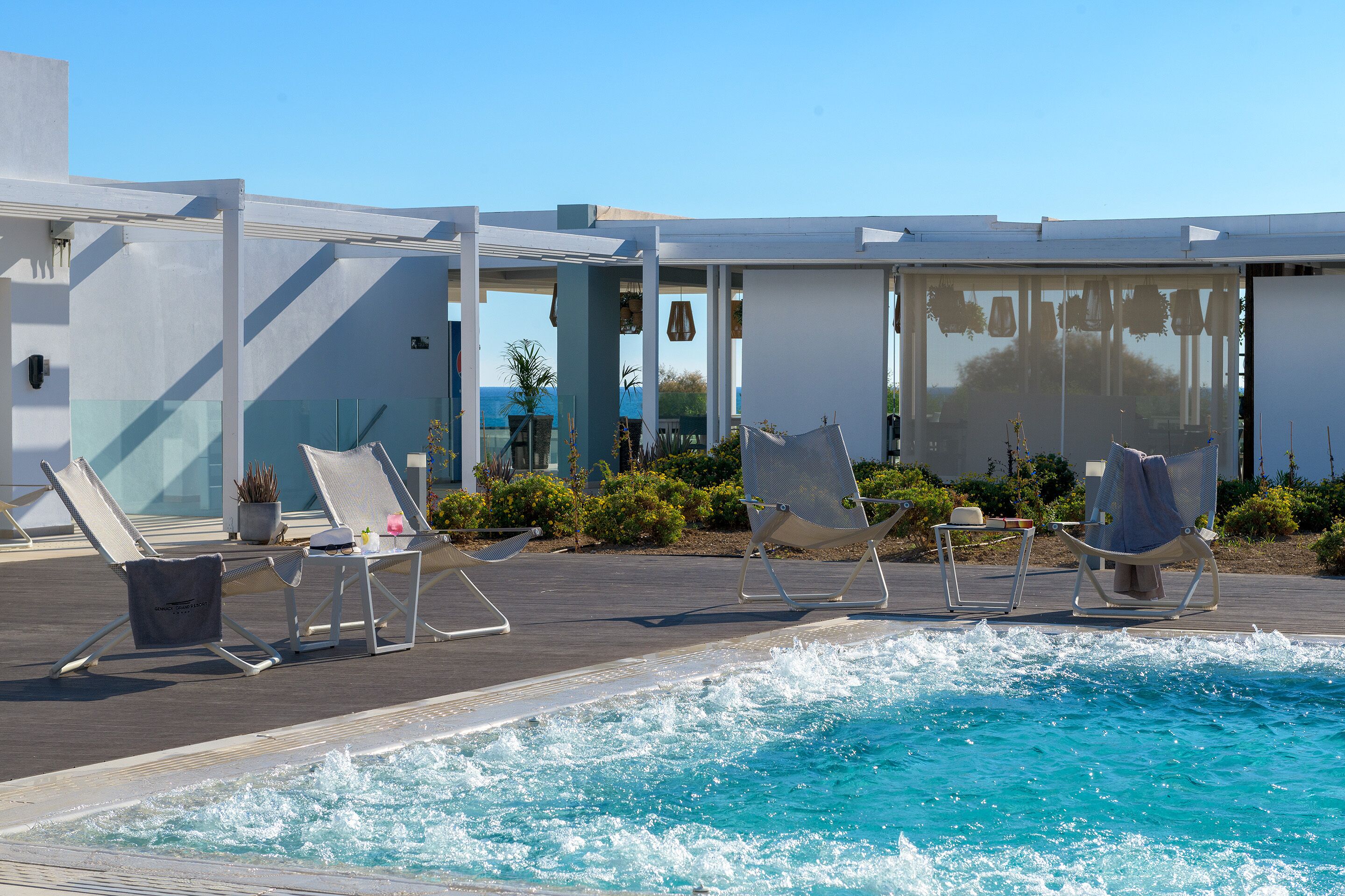 A poolside area with lounge chairs and a glass-enclosed structure.