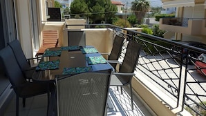 A balcony with a table and chairs, a view of the surrounding buildings and mountains, and a railing. - Geo Maisonette Lagonissi (Saronikos)