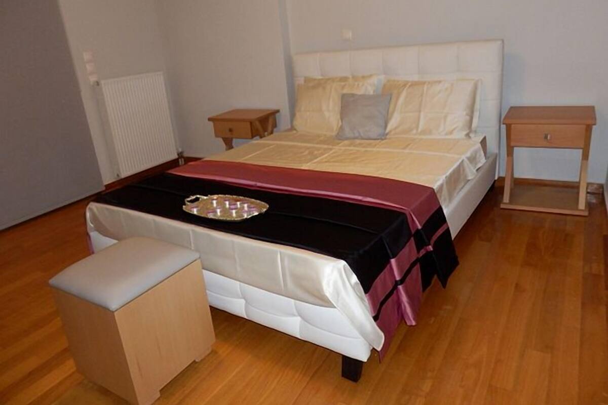 Ein Schlafzimmer mit Bett, Nachttisch, Bank und Heizkörper.
