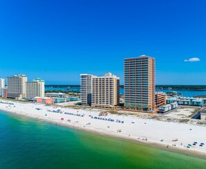 Un paysage urbain côtier avec de hauts immeubles, une plage de sable et un ciel bleu dégagé.