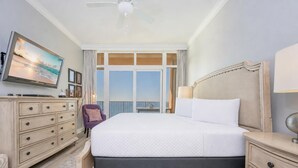 Habitación de hotel con una cama grande, cómoda, televisor y vista al océano.