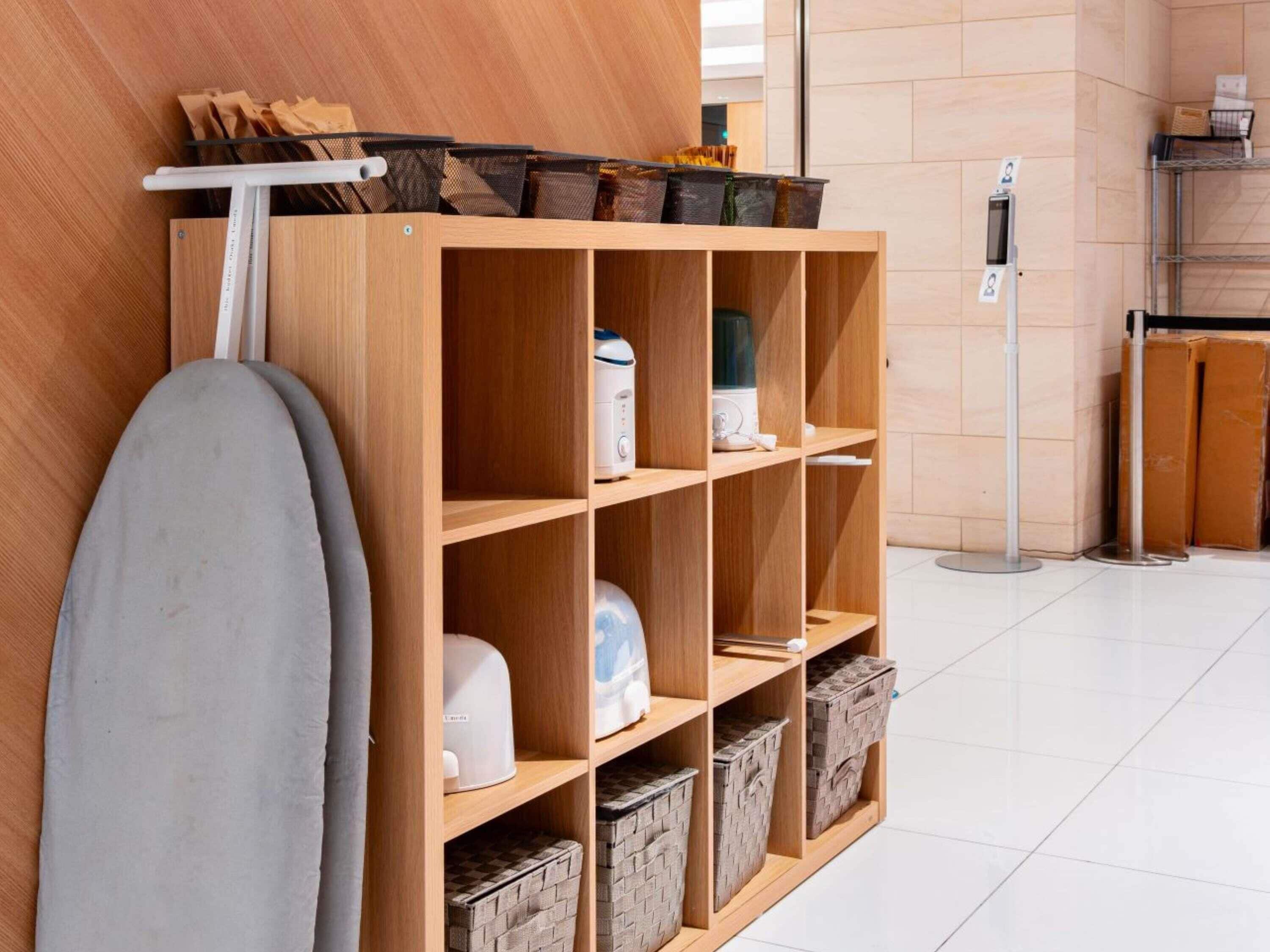 A wooden storage unit with shelves, baskets, and a white appliance, likely a coffee maker, in a clean, modern interior.