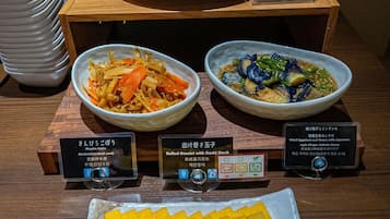 A buffet with various dishes, including a bowl of mixed vegetables, a bowl of fish, and a plate of yellow food.