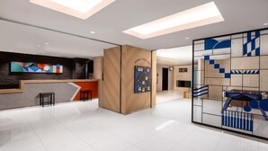Un moderno vestíbulo de hotel con una recepción, un panel de madera y una gran obra de arte abstracto en la pared.