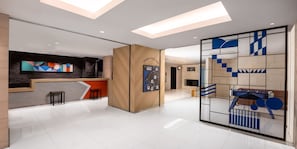 Un moderno vestíbulo de hotel con una recepción, un panel de madera y una gran obra de arte abstracto en la pared.