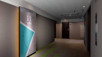A hallway with a sign indicating the 11th floor, a carpeted floor, and a door with a handle.