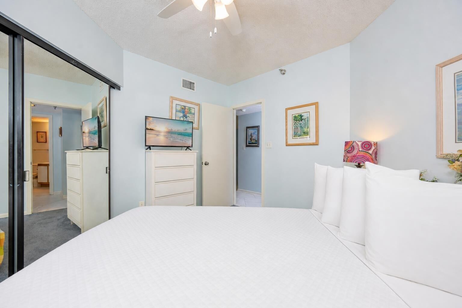 A bedroom with a bed, a dresser, a TV, and framed pictures on the wall.