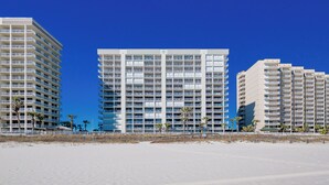 Ein Strandhotel mit mehreren Etagen, Balkonen und Palmen.