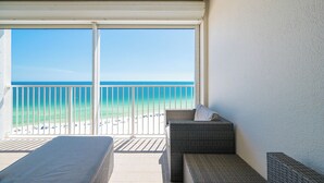 Ein Balkon mit Blick auf den Strand, Korbmöbel und einem weißen Geländer.