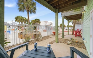 A covered patio with two Lone Star beer cans, a pool area with a fence, and red chairs. - Pool, Near Beach & 4BR Family Retreat - Sailfish (Port Aransas)
