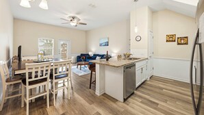 Een moderne keuken met een centraal eiland, een houten eettafel en stoelen.