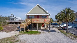A two-story beach house with a wooden deck and a red door. - Prime Beach/Lagoon Location!  Walk to beach and restaurants! (Gulf Shores)
