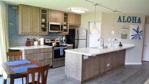 Una cocina moderna con armarios de madera, microondas integrado, estufa y una isla grande con fregadero.